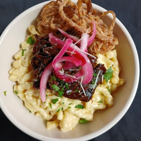Mac and cheese topped with pulled pork, pickled red onions, crispy fried onions, and parsley.